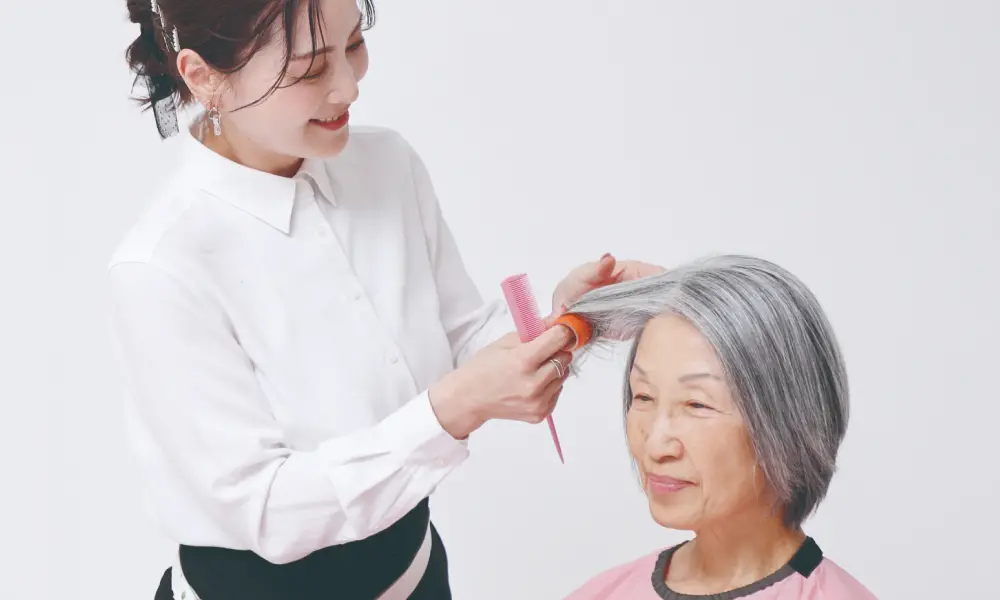 美容師が高齢女性の髪を整えている様子
